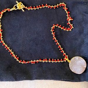 White druzy pendant on gold chain with red beads